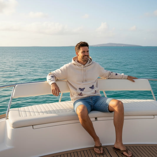 A Brand Called California unisex cream hoodie with butterfly appliques on the front and sleeves, worn by a man on a boat.