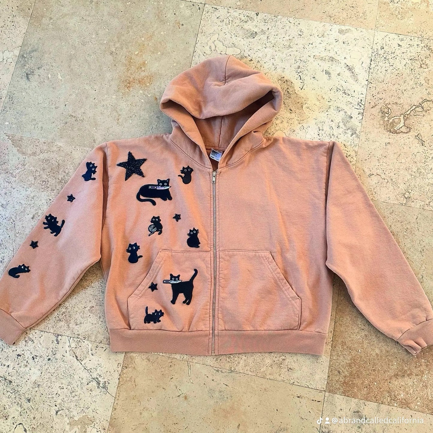 A Brand Called California peach cropped zip-up hoodie with black cat appliques and glitter star detail.