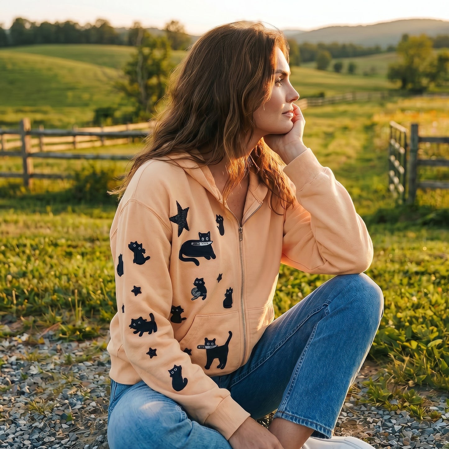 A Brand Called California peach zip-up hoodie with black cat and star appliques. Model wears jeans and hoodie outdoors.